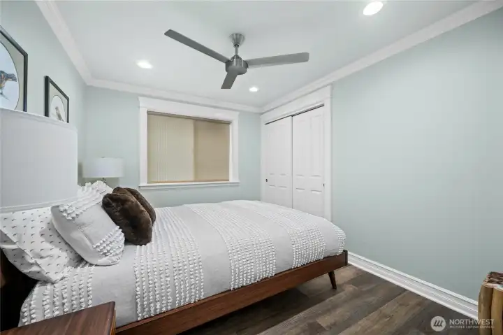 Comfortable guest bedroom with large window, ceiling fan, and closet storage.