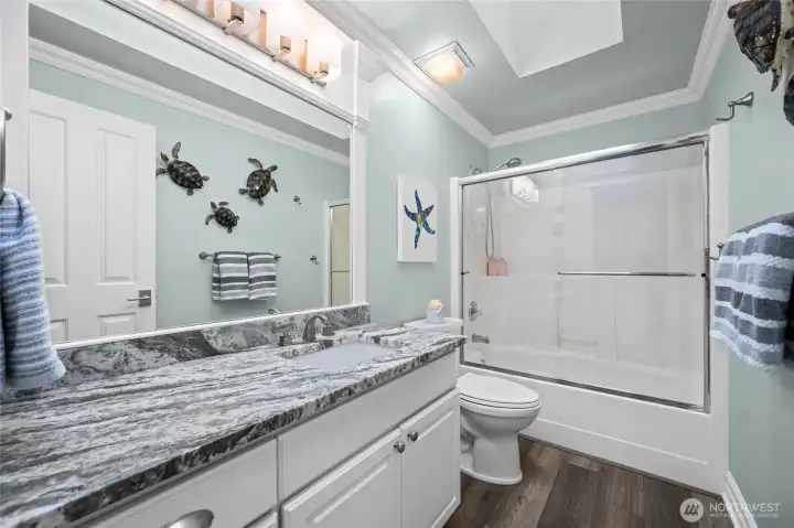 Full bathroom featuring granite vanity, modern fixtures, and tub-shower combination with glass enclosure.