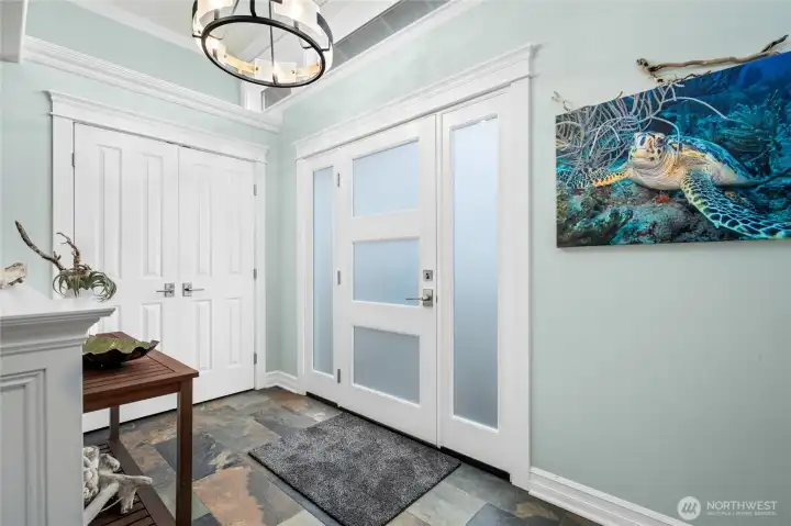 Light-filled foyer welcomes you inside with refined millwork, slate flooring, and modern entry doors, setting the tone for this beautifully updated home.