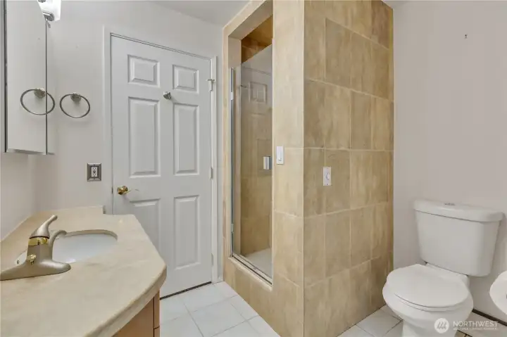 Convenient lower-level bathroom with tiled shower, Corian countertops and upgraded fixtures—perfect for guests or extended living space.