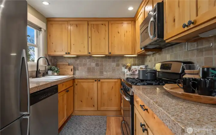 Gas cooking with an overhead microwave as well as granite counters and a tile backsplash.