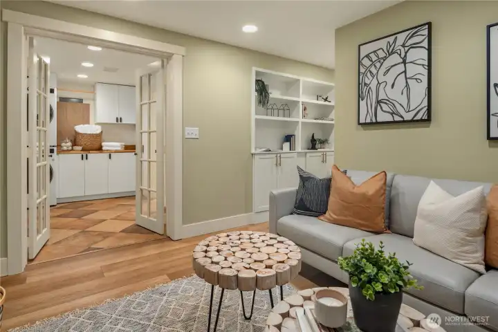 Looking across the lower rec room towards the laundry room and adjacent bath. You can see additional built-in cabinets and shelving in the hallway.