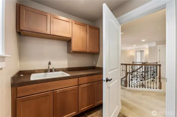 Laundry room with sink and cabinets on upper level.