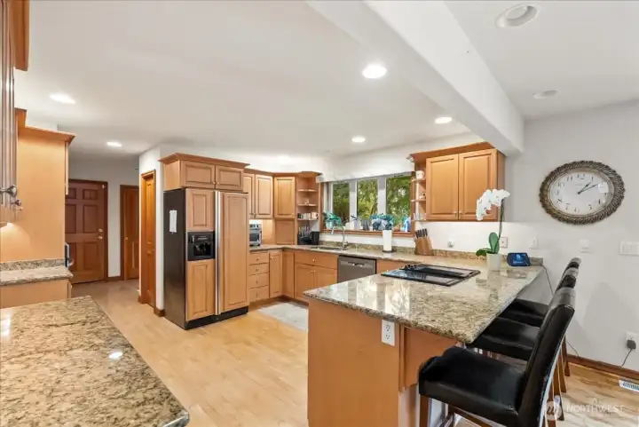 Spacious kitchen features custom cabinetry, granite counters, and abundant storage.