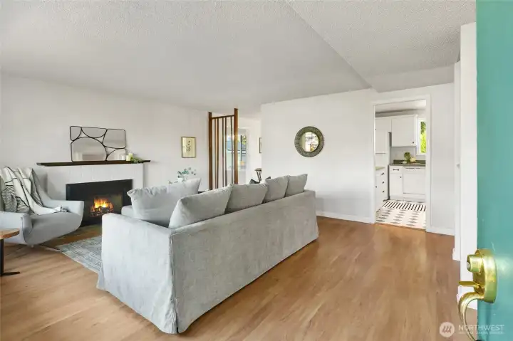 Enter the home into the main living area with a gas fireplace and laminate flooring.