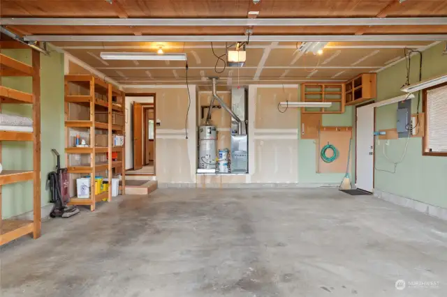Spacious garage with built-in shelving, multiple shop lights and a suction fan. The exterior door leads to the sideyard.