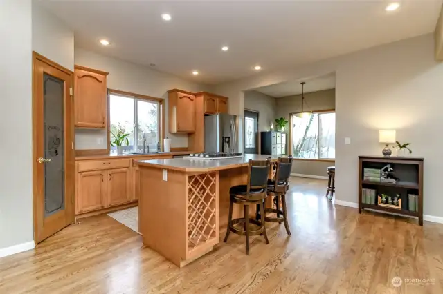 Practical kitchen with island breakfast bar and extra alcove for informal dining beyond.