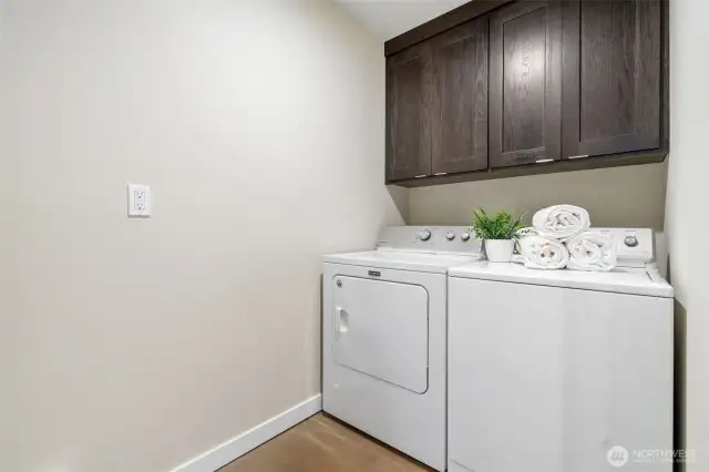 The laundry room offers ample storage with cabinets above, keeping essentials neatly organized. A functional and convenient space designed to make laundry tasks effortless.