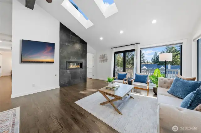 Experience luxury and warmth in this stunning living room, featuring a modern gas fireplace, vaulted ceilings, and skylights that fill the space with natural light.