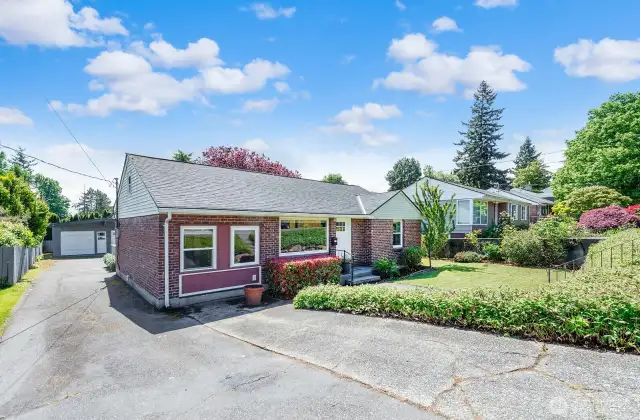 Wide paved driveway with extra parking off street leads to the back yard and an oversize detached two car garage.