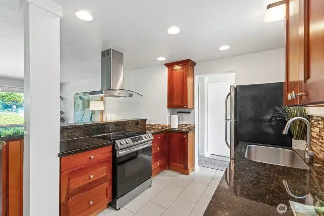 Slab granite countertops, custom cabinets and stainless appliances. Big farm style sink with tile backsplash.