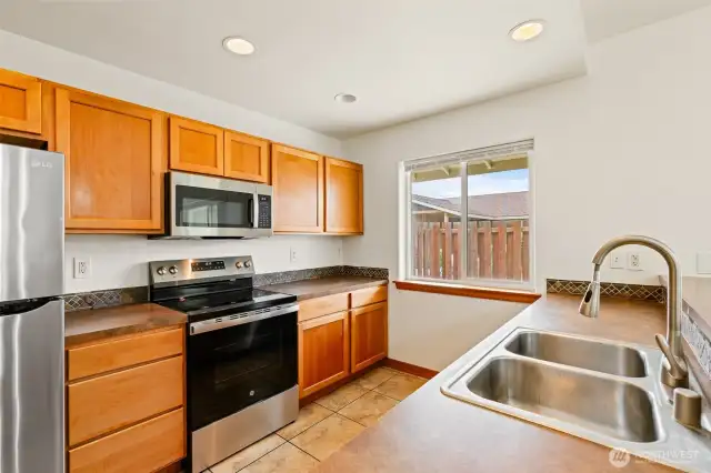 Tiled kitchen with range, refrigerator, dishwasher and microwave.
