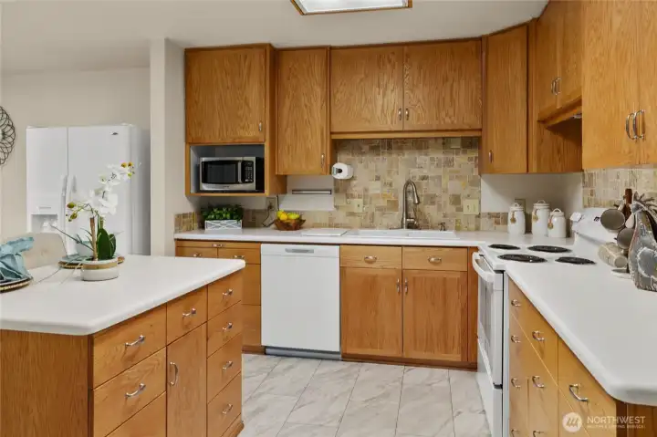 The updated spacious kitchen features newer appliances, corian countertops, tile backsplash.