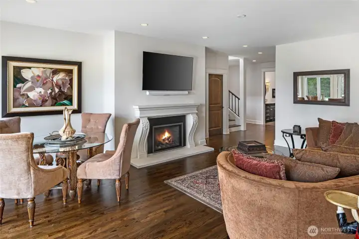 Open-concept living and dining area featuring hardwood flooring, elegant fireplace surround, recessed lighting, and seamless access to outdoor entertaining spaces.