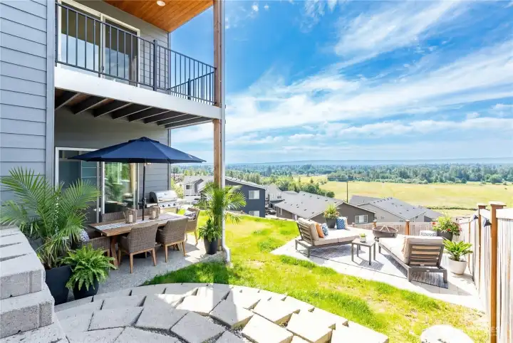 Virtually staged covered patio and concrete pad for outdoor living space, trampoline, kids play set with the incredible views