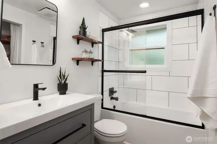 Updated main-floor bathroom featuring a beautifully tiled tub and shower surround with stylish, modern finishes.