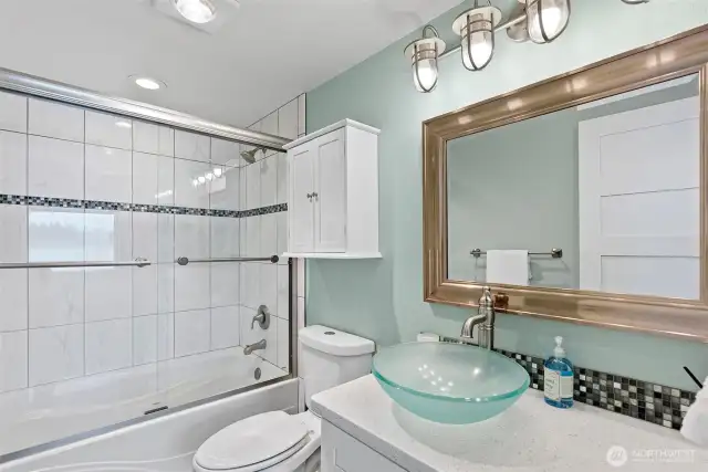 The bathroom on the main level has been refreshed with quartz countertops, a vessel sink, tile surround in bath tub/shower, and much more.