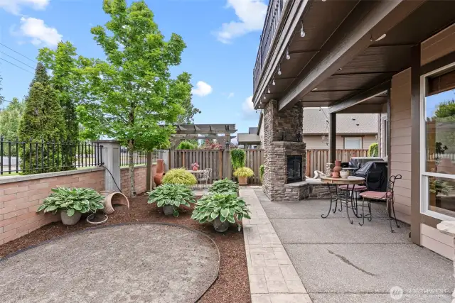 Stone detail surrounds the outdoor fireplace; outdoor kitchen includes built-in grill and prep counter located just off breakfast nook.