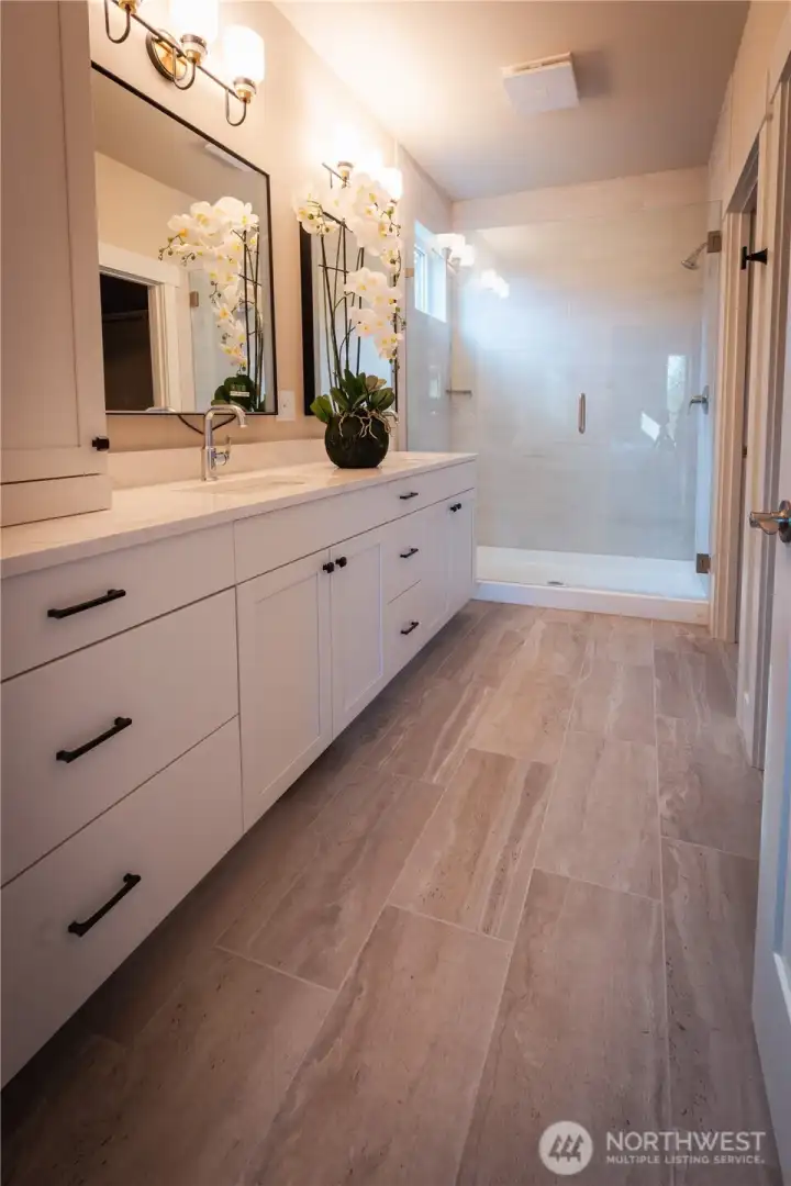 Designed with both comfort and style in mind, the primary bathroom features a large walk-in tiled shower and quality finishes throughout. The vanity space is well-appointed, offering both functionality and a touch of everyday luxury.