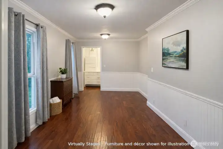 Main-floor bedroom with hardwood floors, natural light, and a walk-in closet