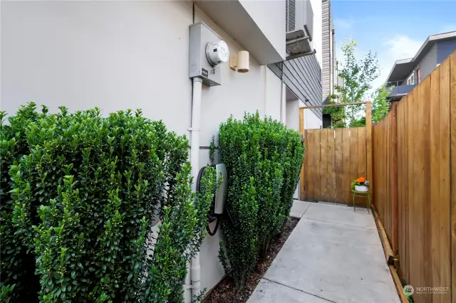 A private walkway leads to the front door and back fenced yard.  Note: there is an EV charger on the wall.