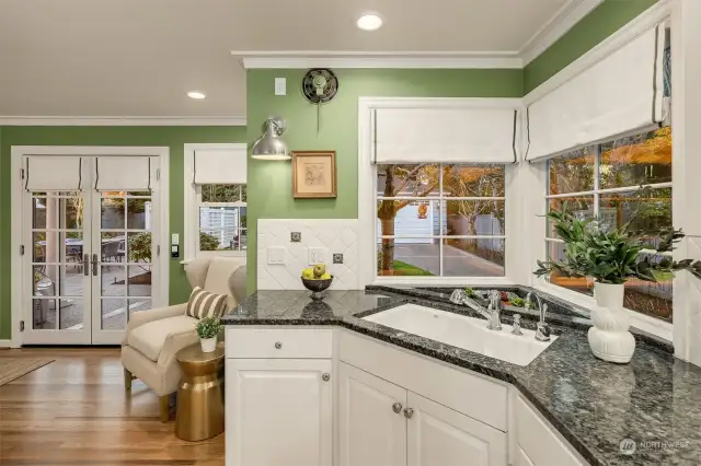 Heading into the kitchen from the dining room, notice all the windows, custom window coverings and French doors leasing to the backyard.