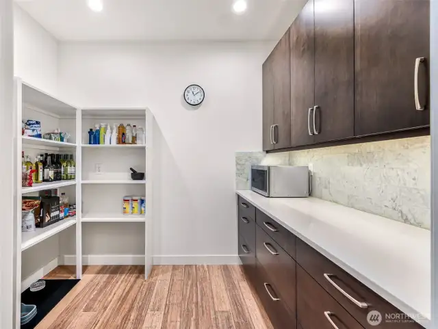 Butler's pantry with additional cabinets, countertop for prepping and food storage.