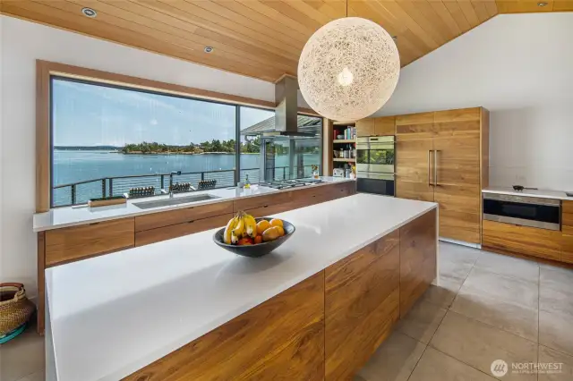 The light-filled chef's kitchen with timeless views is an absolute chef's delight. It features walnut cabinetry, a center island, high-end appliances, prep sink with refrigerator drawers and double ovens.