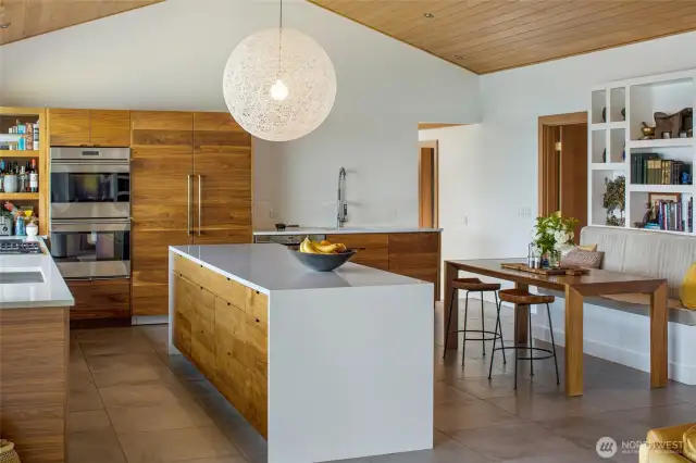 Another view of the kitchen, looking towards the prep sink, dining area and entry. The walnut cabinetry offers plenty of storage, double refrigerator, double oven.