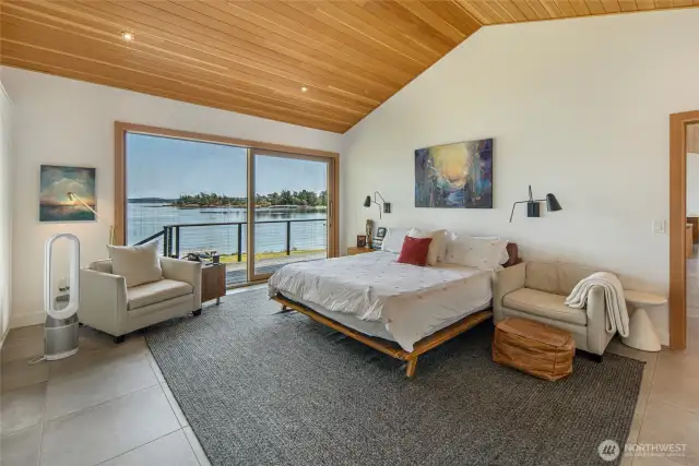 The primary bedroom with sliding doors to the deck. Wake up to serene views.