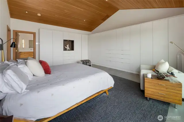 The primary bedroom features abundant built-in closet space, vaulted clear fir ceilings and recessed lighting.