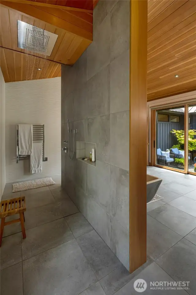 The walk-through shower with rain shower head and towel warmer. On the right a glimpse to the inner courtyard.