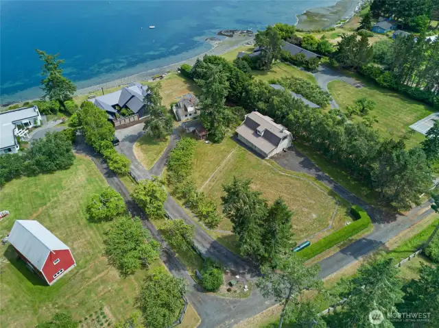The property features two paved driveways. One going to the barn-style shop and garage, the other is a circle driveway leading to the main house and farmhouse.