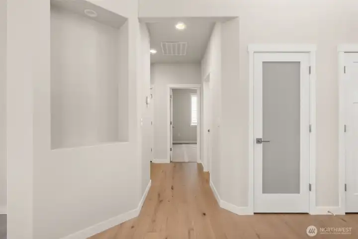 Decorative wall niche and pantry closet with solid shelving and frosted glass door for easy access from kitchen.