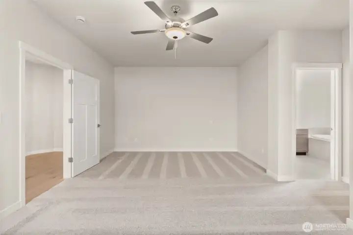 Inviting and spacious primary bedroom with ceiling fan for added comfort.