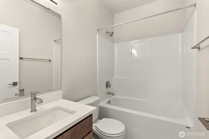Full bathroom with undermount sink in Shadow-stained Maple cabinet, quartz countertop with backsplash and tub/shower.