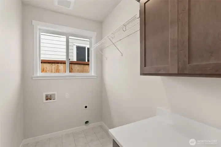 Separate laundry room with cabinets and a high hanging shelf for extended storage.