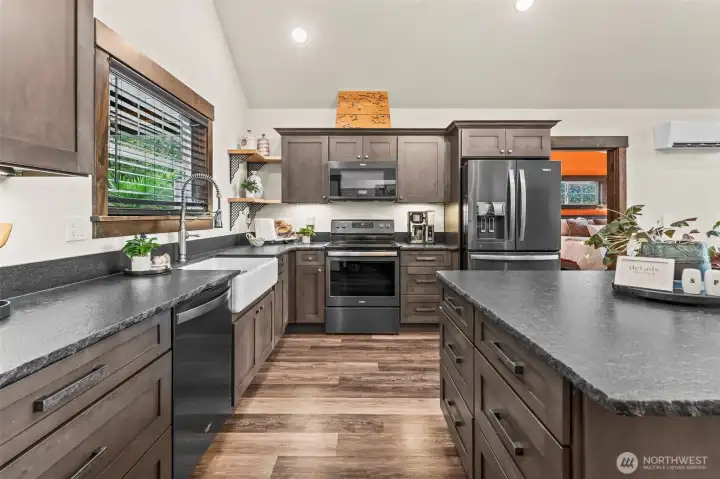 This thoughtful kitchen features a deep farm sink, plenty of cabinets and drawers all with soft close, live edge granite countertops and worm wood accents.