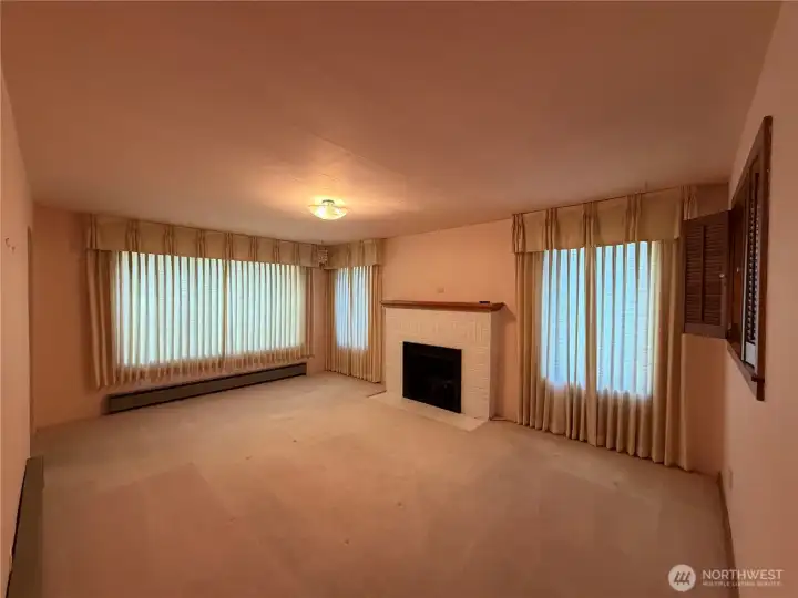 Formal living room with fireplace. Main entrance at left and passthrough from kitchen to living room at right. Formal living room with fireplace. Main entrance at left and passthrough from kitchen to living room at right.