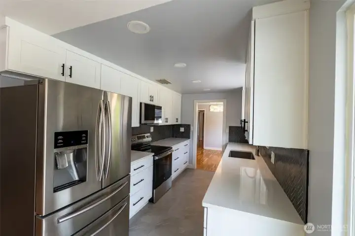 Kitchen view one, nicely updated! Quartz countertops, matching included stainless steel appliances, updated lighting, cabinets, ready to go for your gatherings.