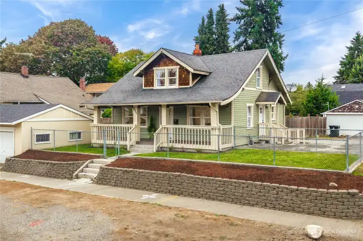 Front of home w/ large covered front porch, fenced yard and 1 car garage.