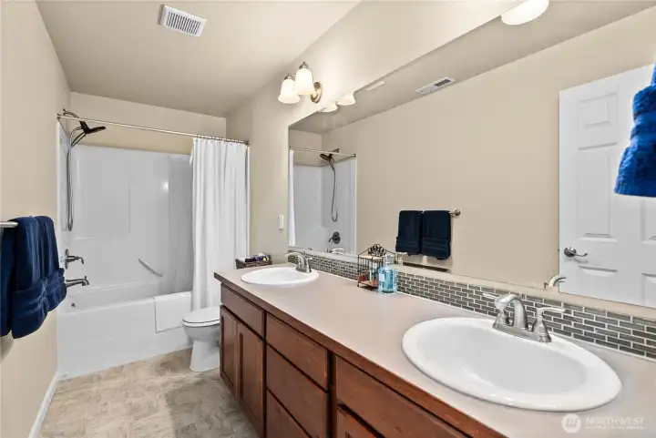 Full guest bathroom featuring a large dual vanity, generous counter & storage space, and a tub/shower combination.