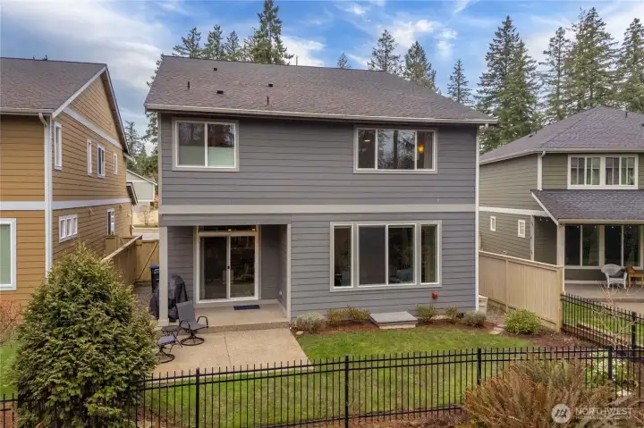 Rear view of the home showcasing the patio, easy-care yard, and tranquil natural setting.