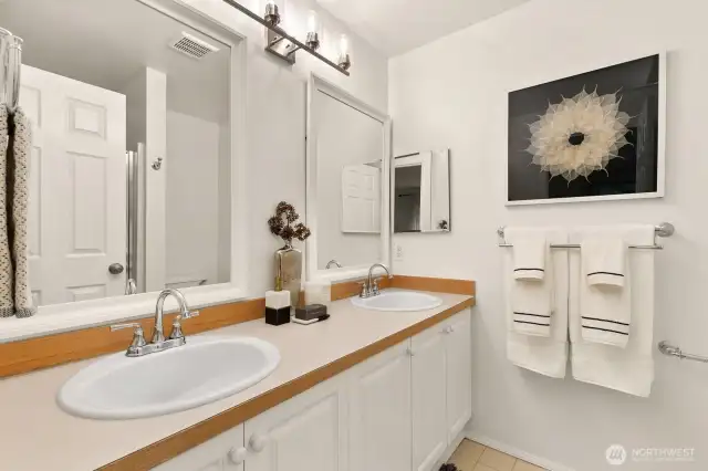 Primary en suite features double vanities and shower (seen behind door in reflection).