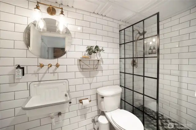 Newer renovations. Bathroom with wall to wall subway tile with marble accents, wall hung fixtures, newer light fixtures, shower with marble niche