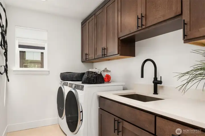 Laundry room is conveniently located upstairs and has beautuful cabinetry, utility sink and comes with a front loading washer and dryer
