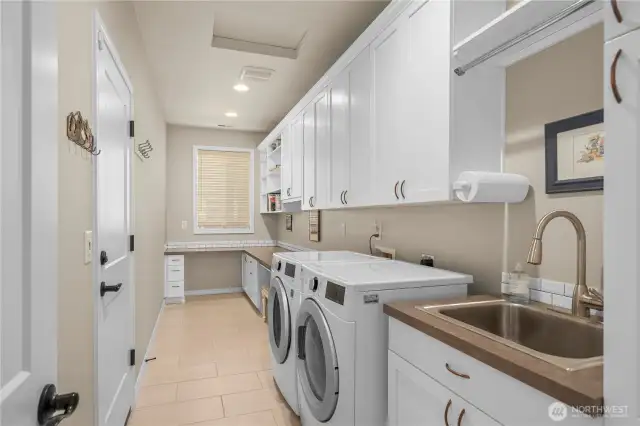 The popular multi-purpose Smart Space.  A laundry/craft/workspace all in one! Tiled flooring, large utility sink, hanging bar and tons of storage.