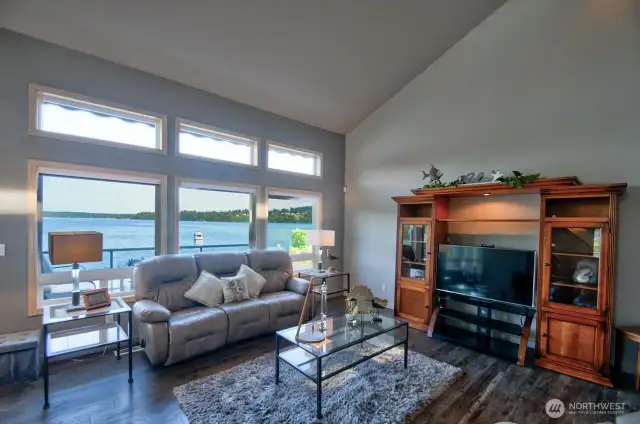 cozy living space with panoramic water views, vaulted ceilings and natural light pouring through picture-perfect windows