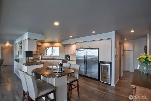 sleek gourmet kitchen with stainless steel appliances, granite counters, wine fridge and inviting island perfect for entertaining