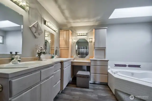 spacious primary en -suite with dual vanities, built in vanity seating and elegant lighting for a spa- like retreat